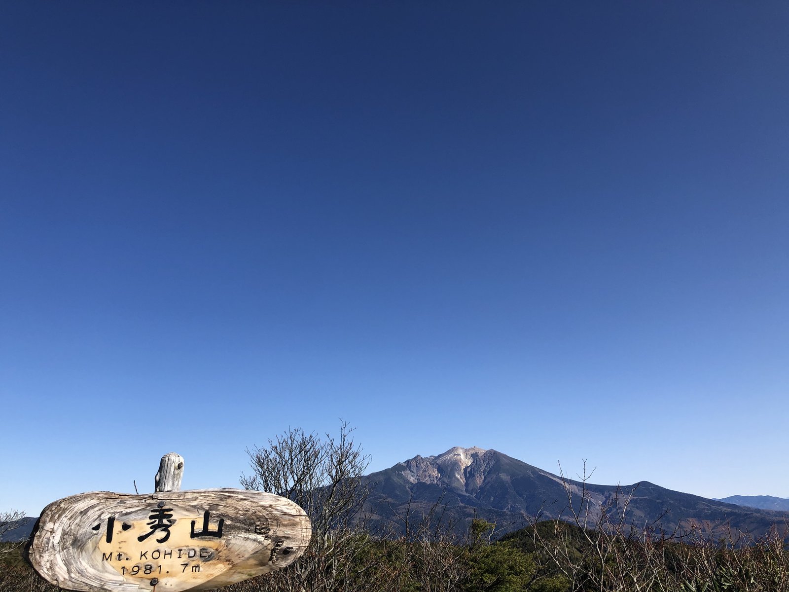 小秀山山頂の丸太の山頂標識と奥にそびえる御嶽山