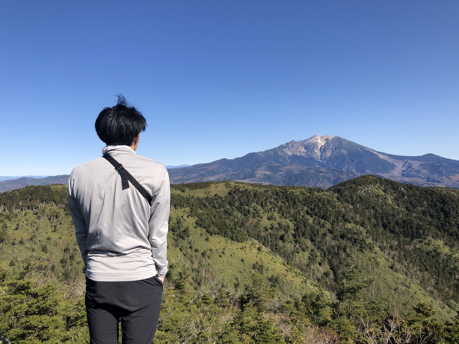 小秀山の山頂で御嶽山を眺める筆者の後ろ姿